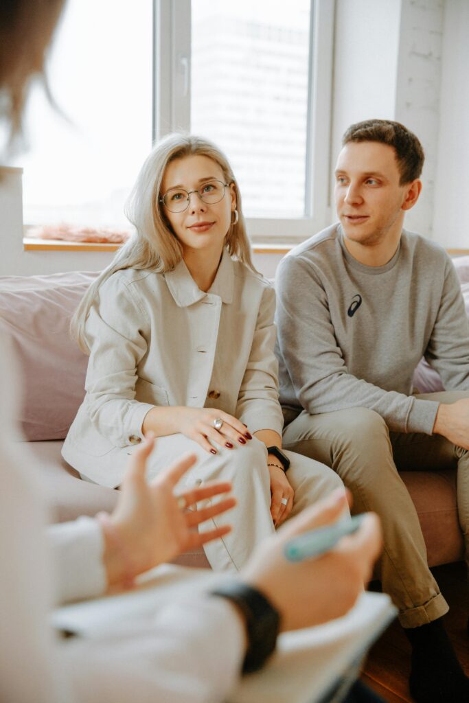 A couple engaged in a therapy session with a therapist indoors.